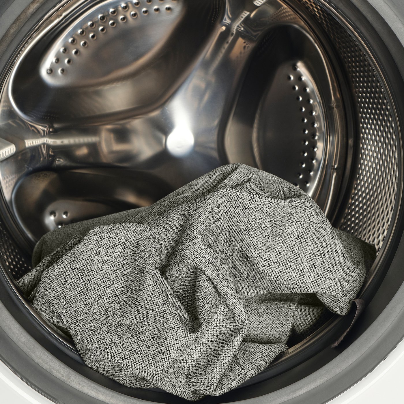 Image shows a washing machines drum with a grey cloth inside.