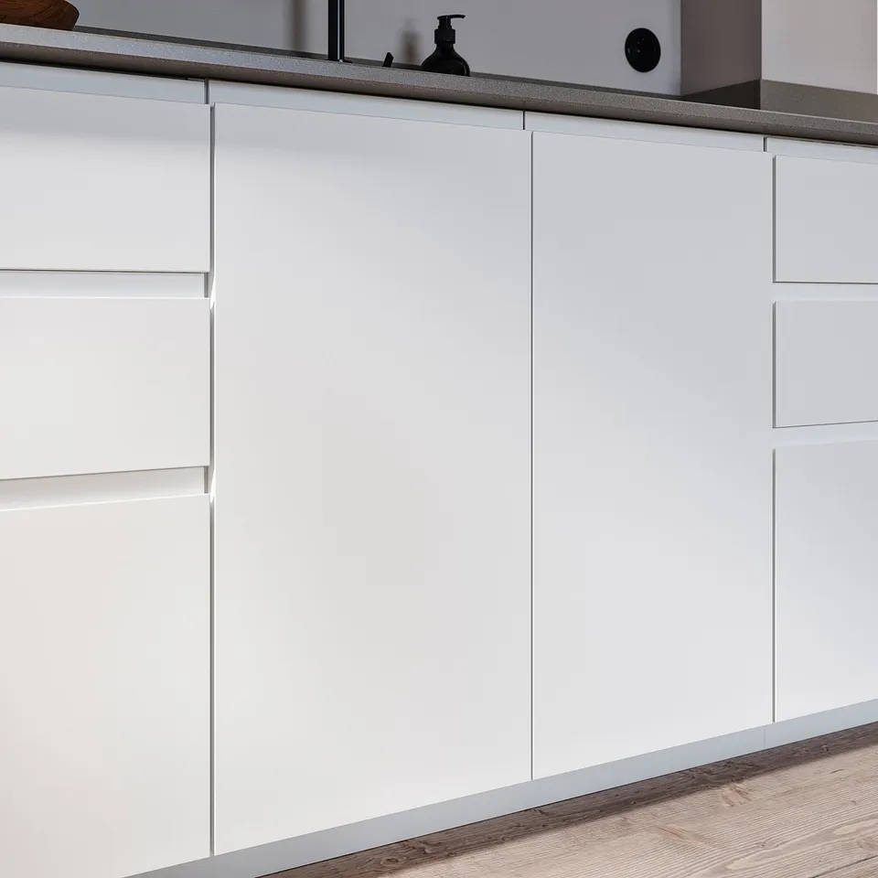 Modern white kitchen cabinets with minimalist integrated handles.