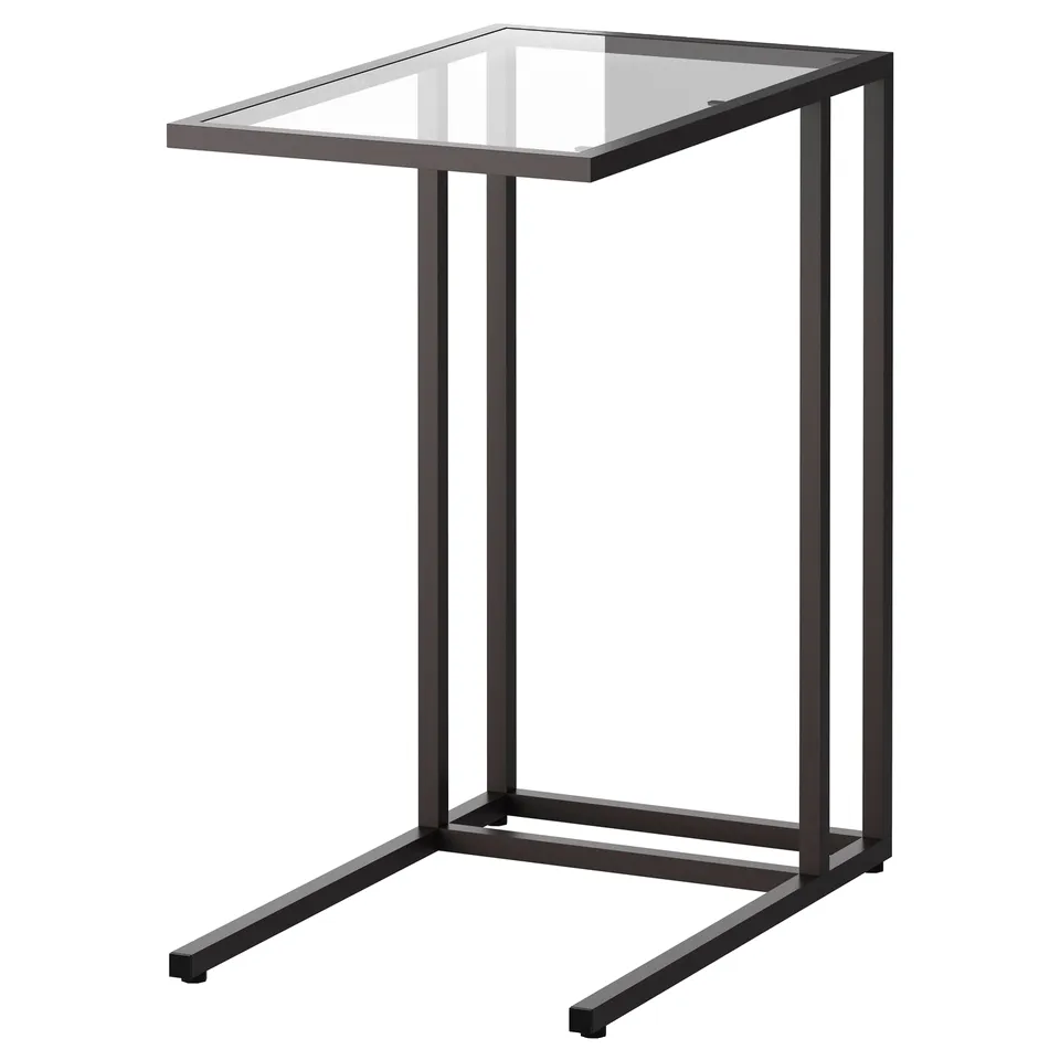 Black VITTSJÖ laptop stand with glass top and metal legs, modern home office setup.