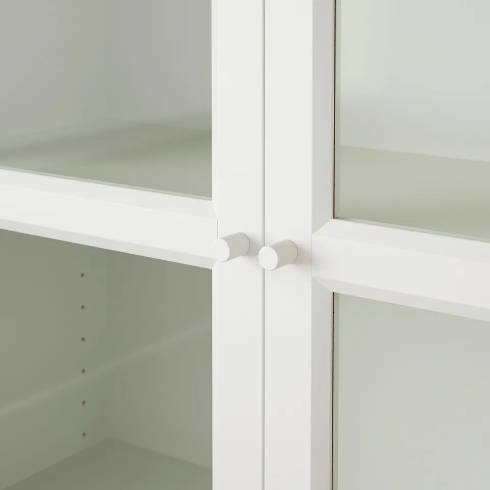 Clean, white bookcase with glass doors, showcasing organised shelves, highlighting its sleek and modern design.