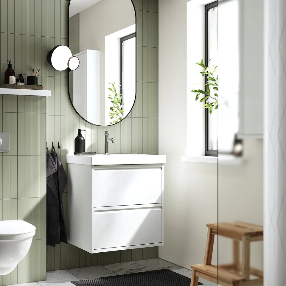 Modern white bathroom cabinet with green tiles, black accents, and large mirror.