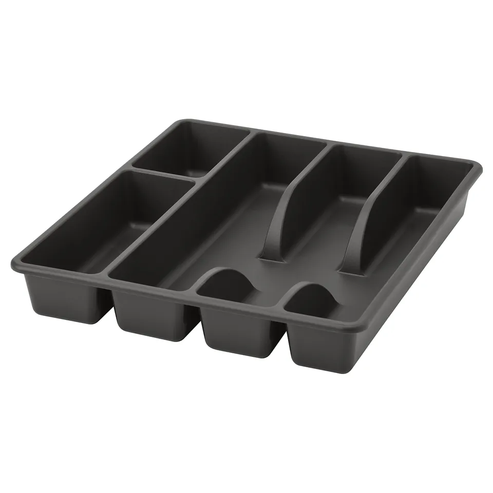 A black SMÄCKER cutlery tray, made of recycled plastic, designed to organise kitchen drawers. It has five compartments and rounded corners.