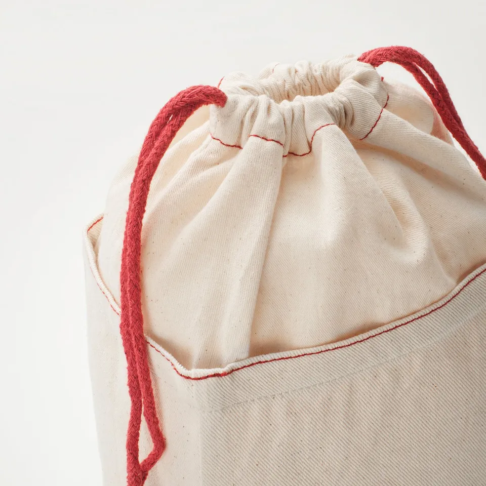 A high-quality cotton storage bag with red drawstrings, neatly closed and detailed stitching.