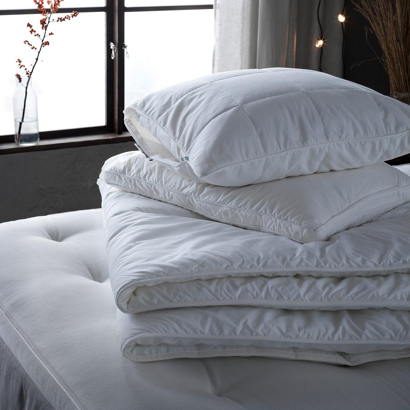 A stack of white STJÄRNBRÄCKA duvets. Soft, fluffy, and breathable, made of lyocell and cotton.
