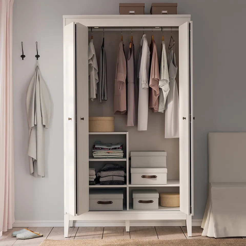 White IDANÄS wardrobe, open showing clothes and storage with shelves and boxes.