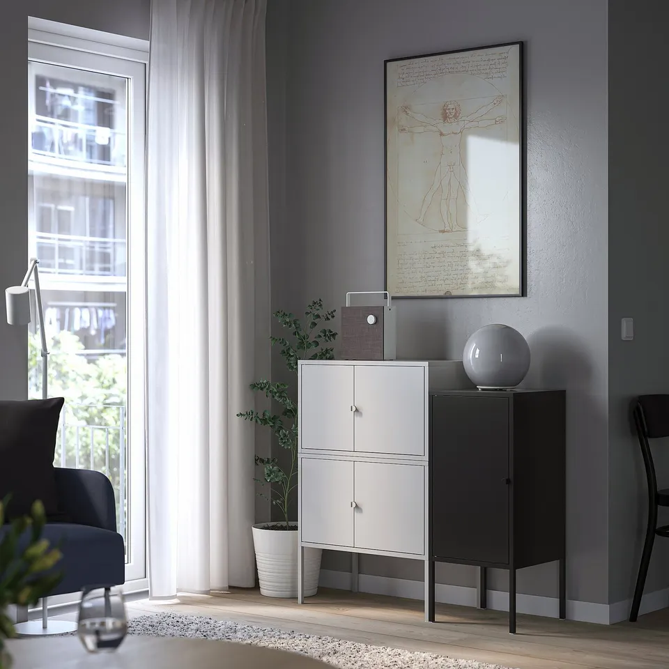 White LIXHULT cabinet by window, grey wall, black chair, plant, modern decor.