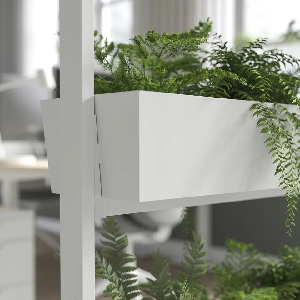 Modular room divider with white frames and lush green plants, enhancing focus and well-being in workspaces.