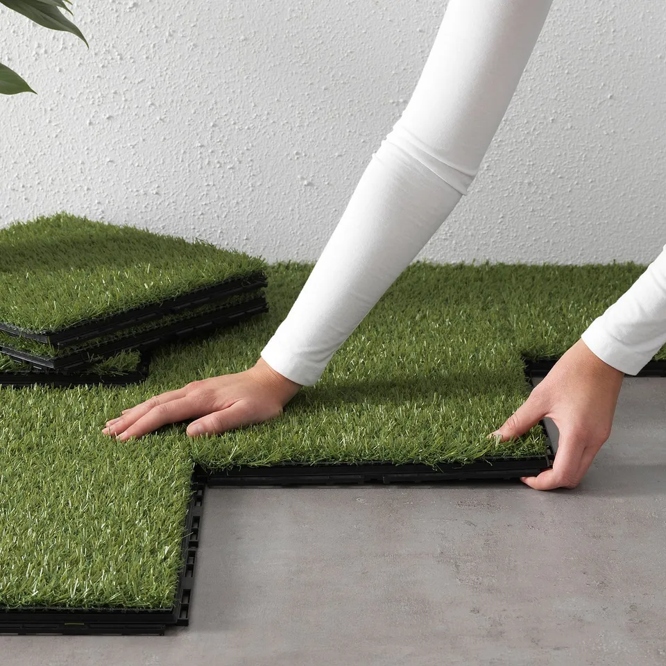 Installing RUNNEN grass tiles on balcony for easy outdoor space.