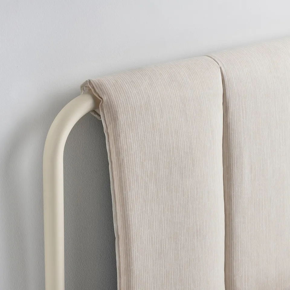 A close-up of a beige upholstered headboard, showcasing its clean lines and soft fabric.