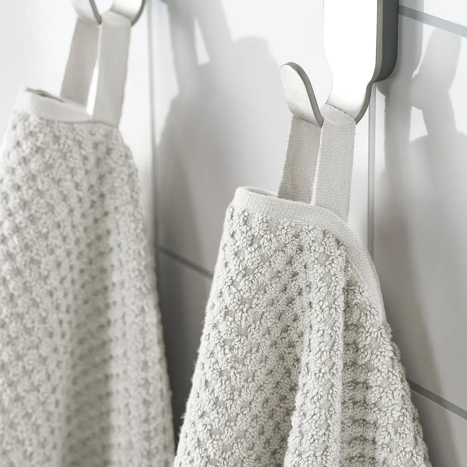 Two beige towels hang neatly, displaying plush, absorbent texture and durable cotton.