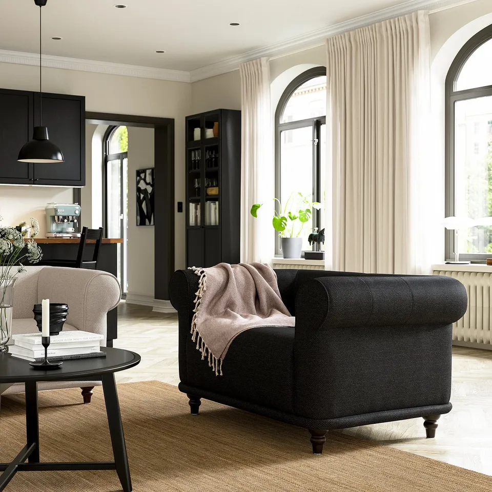Cosy living room with arched windows, armchair, coffee table, and bookshelf.