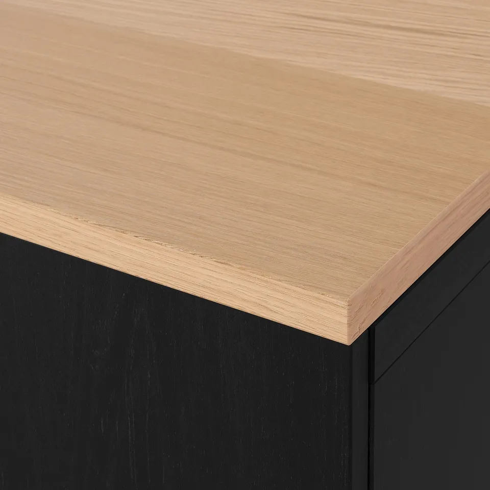 Close-up of sleek, light wood tabletop with smooth, bevelled edge atop modern, dark base.