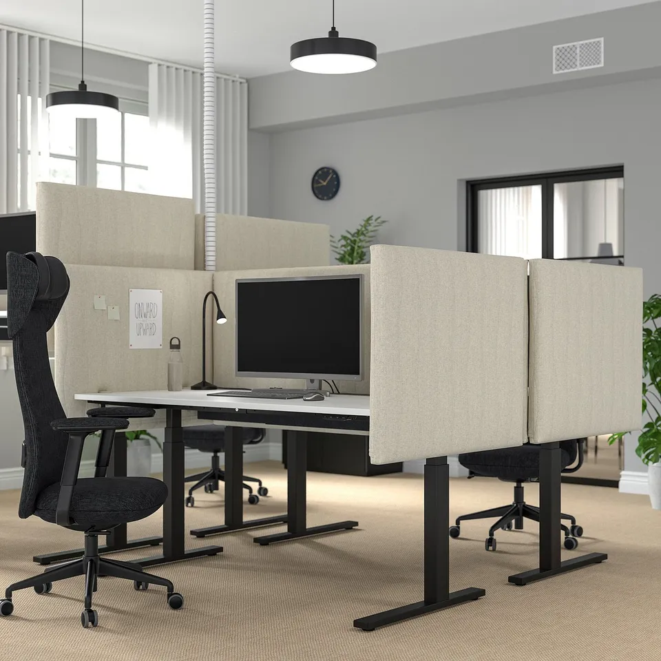 Modern office with MITTZON sit-stand desks, ergonomic setup, large windows, black chairs, plants, clock. Well-being focus.