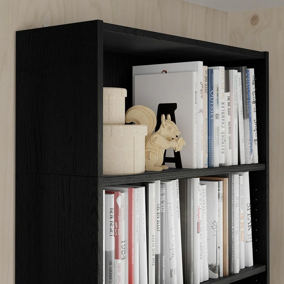 Black bookshelf with books, boxes, and a wooden horse figurine.