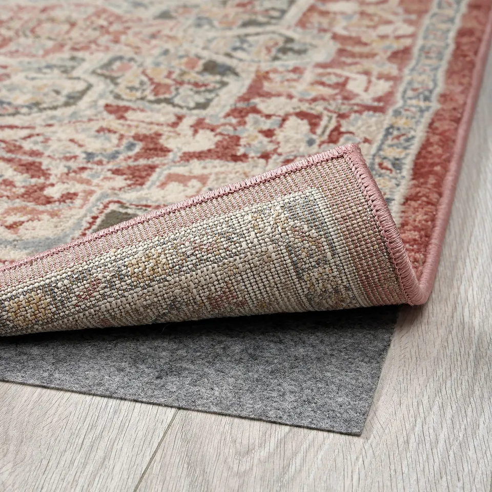 Decorative rug with intricate patterns, showing durable backing on wooden floor.