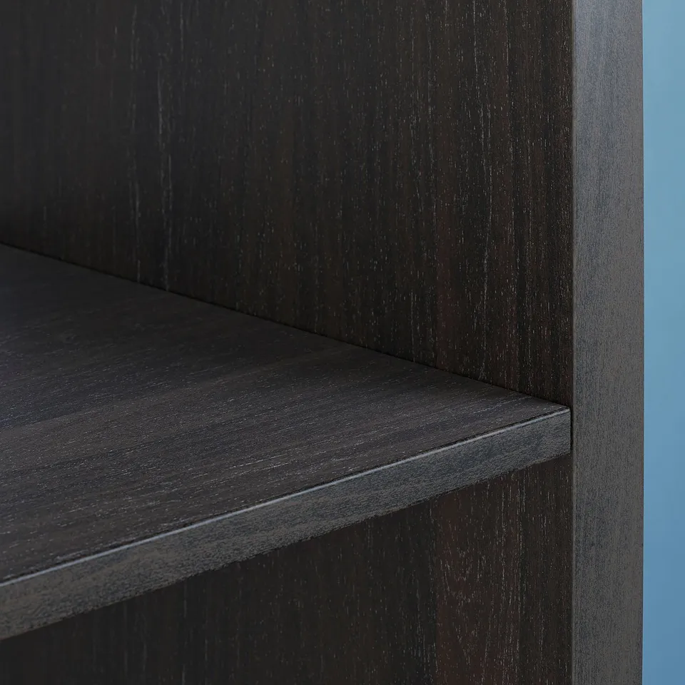 Black KALLAX shelf, close-up. Dark wood grain texture and sleek edges, set against a blue background.