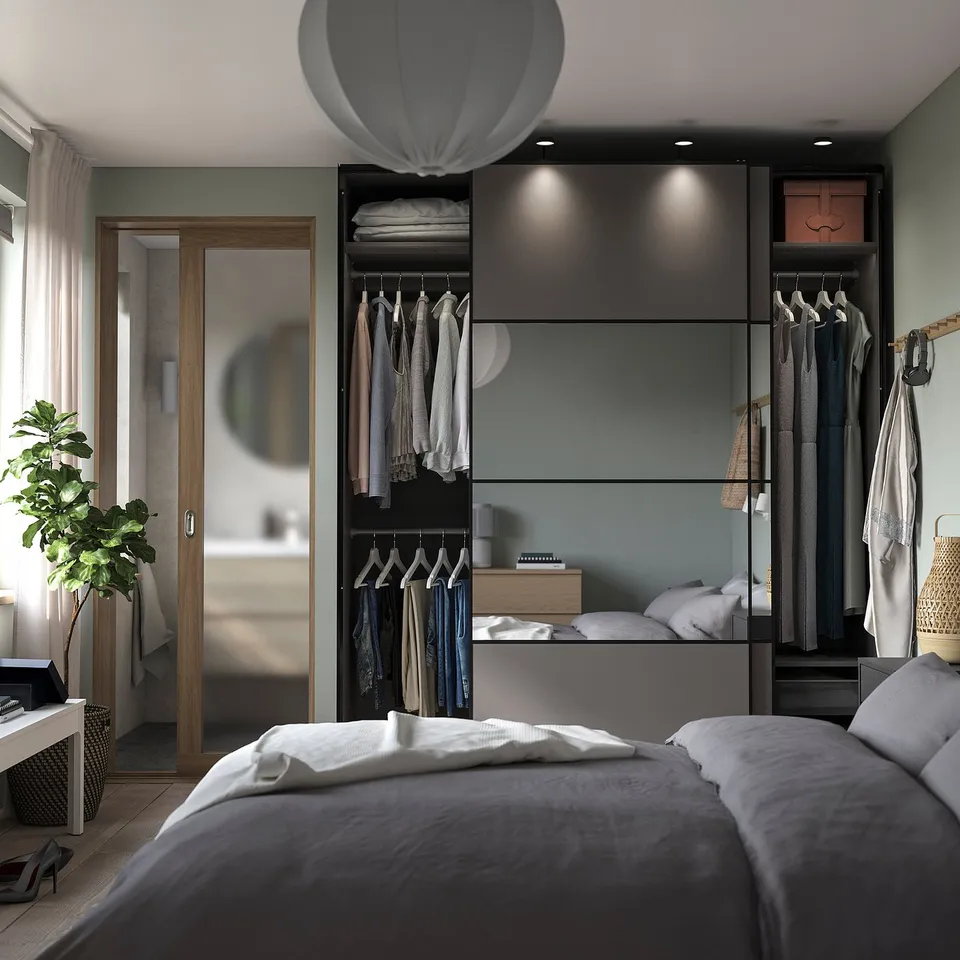 Modern bedroom with grey PAX wardrobe, sliding doors, wooden accents, white bedding, and minimalistic decor.