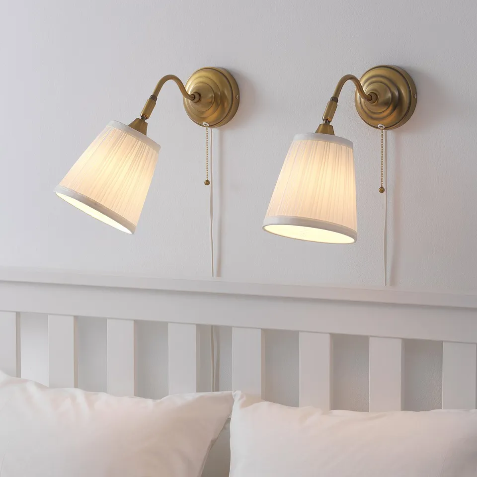 Two vintage-style wall lamps above a bed, with adjustable necks and beige shades, casting a warm light.