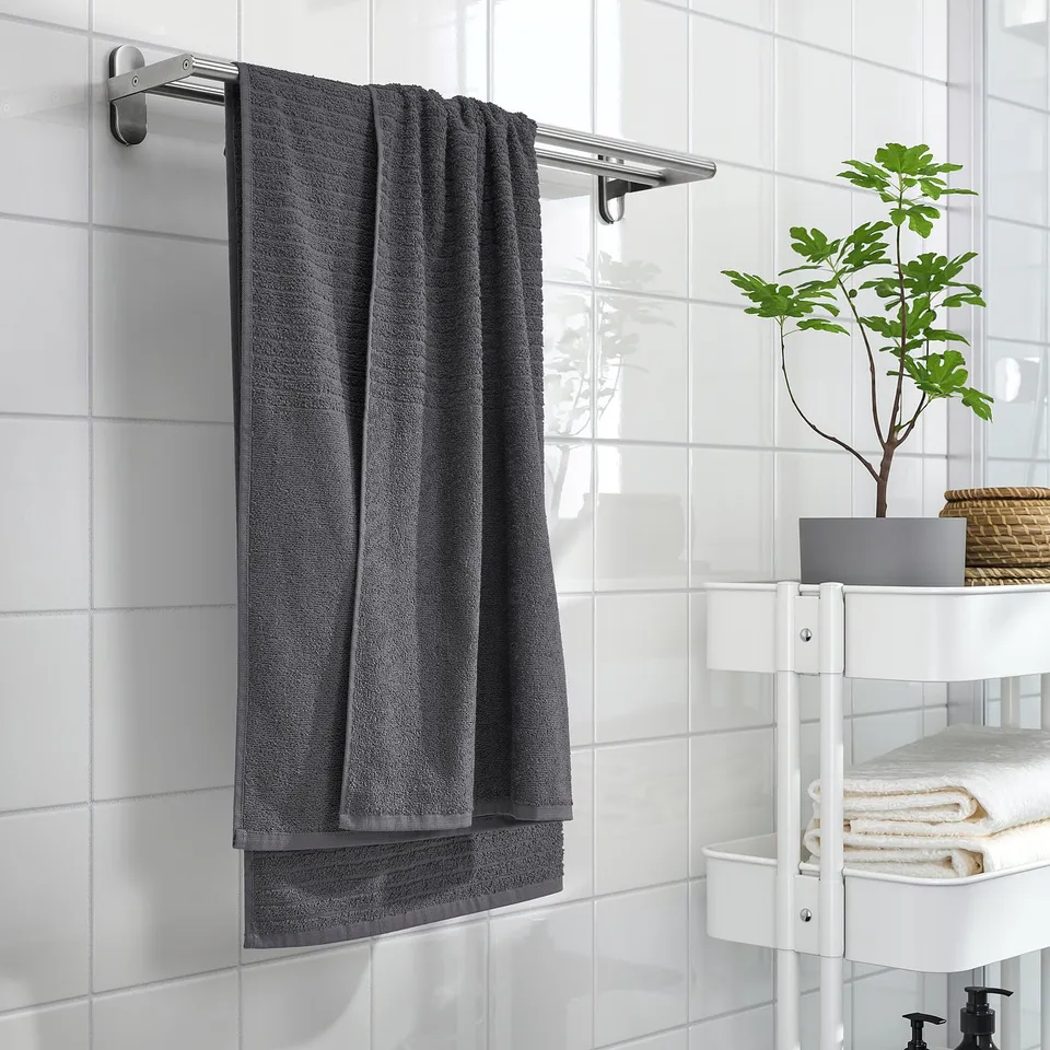 Grey cotton towel on metal rack, folded, near bathroom window with plant.