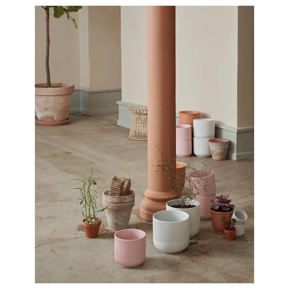 Potted plants in colourful, grooved GRADVIS pots around a column.
