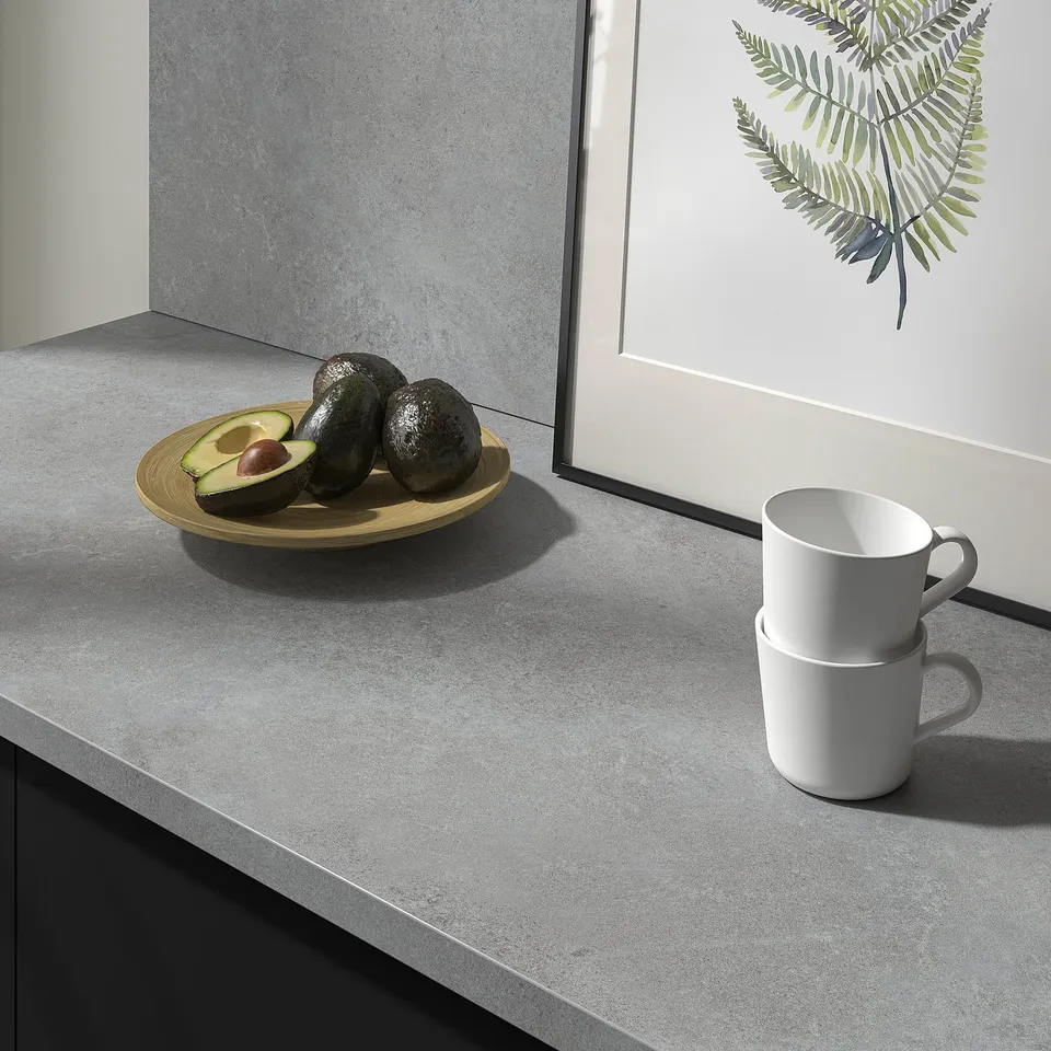 Grey kitchen countertop with two stacked white mugs and a wooden plate of avocados.
