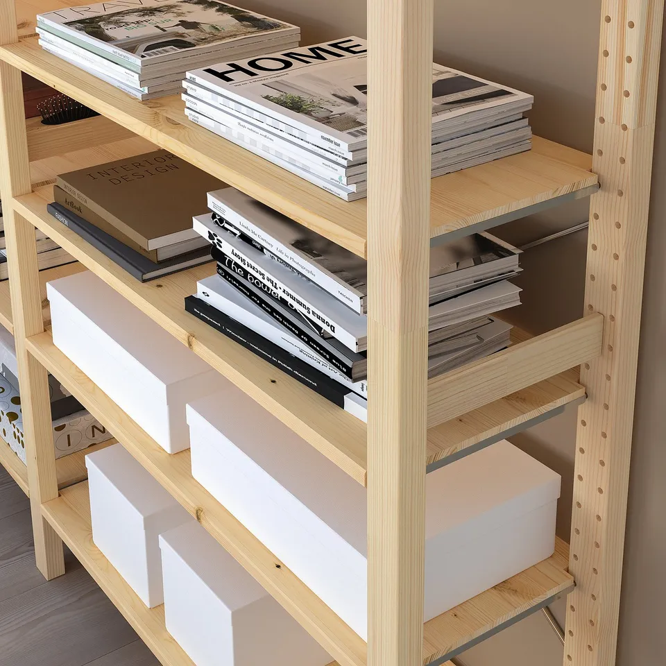 A wooden bookshelf named IVAR, holding books and storage boxes, with adjustable shelves.