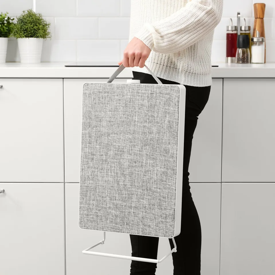 A person carrying a portable air purifier with a handle, suitable for moving between rooms.