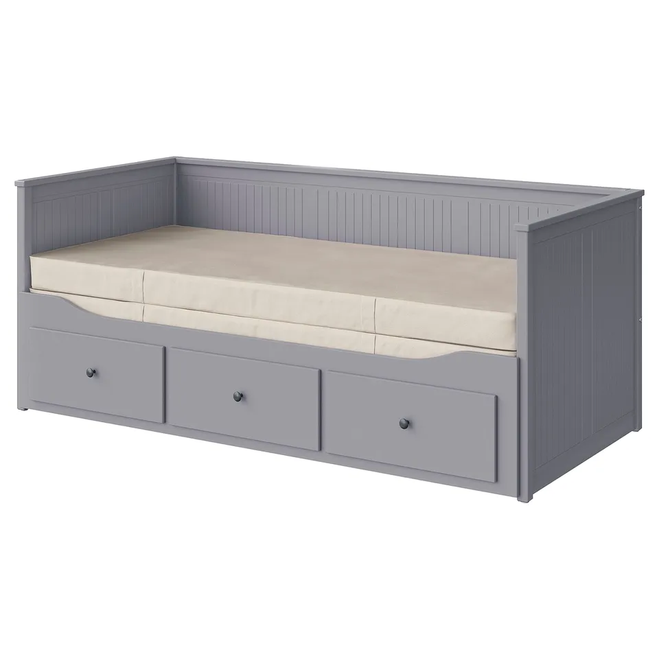 A grey HEMNES day-bed with three drawers and a beige mattress. It has a wooden frame and vertical panel design.