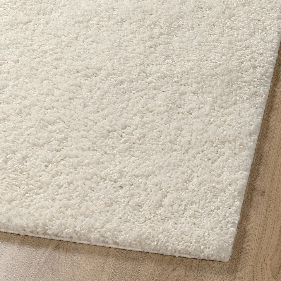 Soft, plush, off-white rug with shaggy texture. Ideal for comfort and sound dampening.