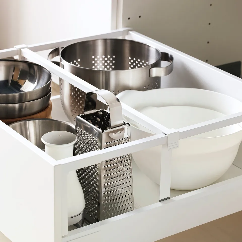 Open kitchen drawer with pots, graters, strainer, and bowl. Items organised for easy access.