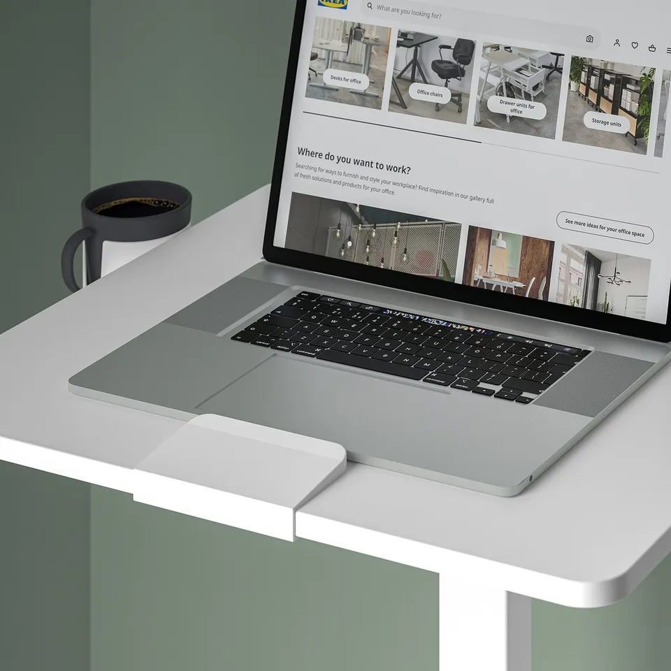 Laptop table with adjustable height, ideal for workspaces. It shows a laptop and a mug on a height-adjustable table.