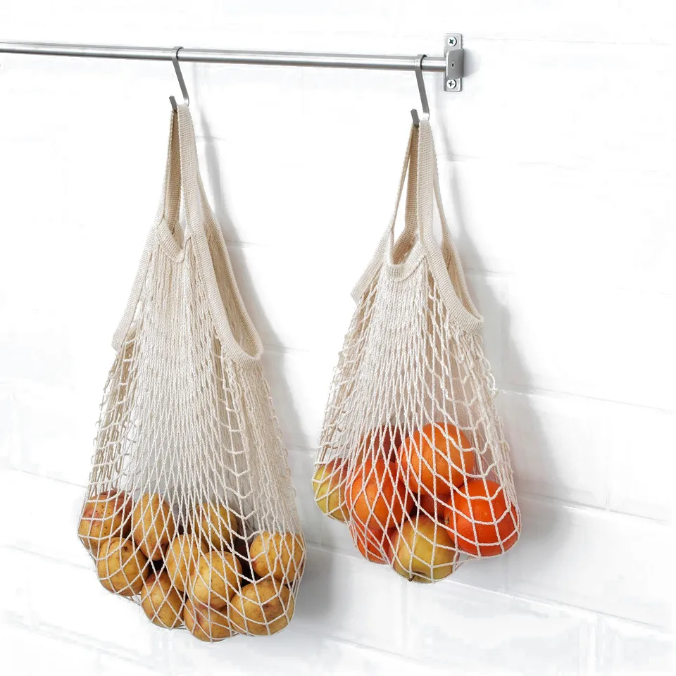Two KUNGSFORS net bags hang from hooks, each filled with fruits and vegetables. The bags keep produce fresh by allowing air circulation.
