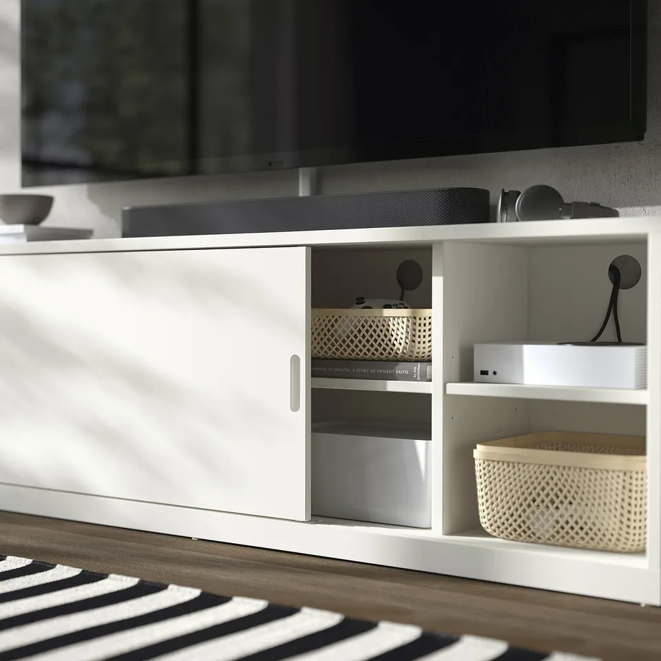 Modern off-white TONSTAD tv stand with open and closed storage, holding electronics and baskets.