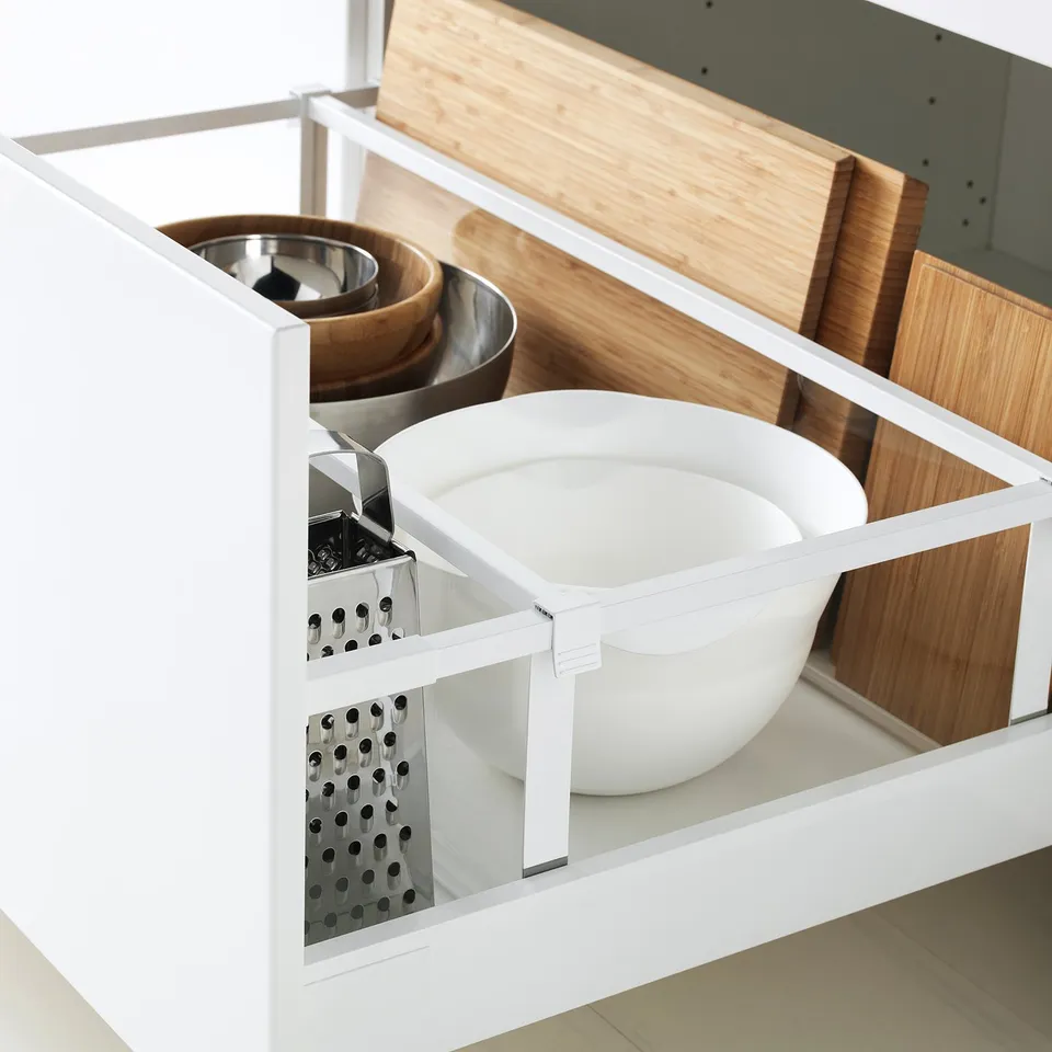 White kitchen drawer organising bowl, grater, cutting boards; self-closing, smooth-running