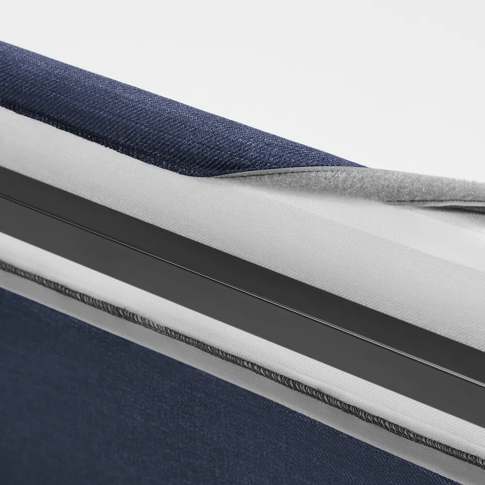 Close-up of bed frames padded, removable cover, showcasing its soft, curved headboard and piped edges.