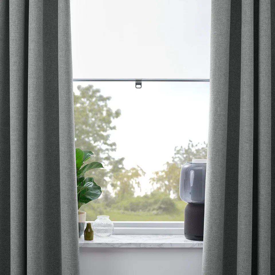 Window with grey curtains, small plants, vase, air purifier, showing block-out feature.