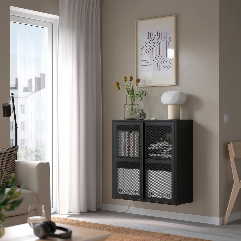 Black IVAR cabinet on wall, poster, lamp, tulips, window, chair, camera.