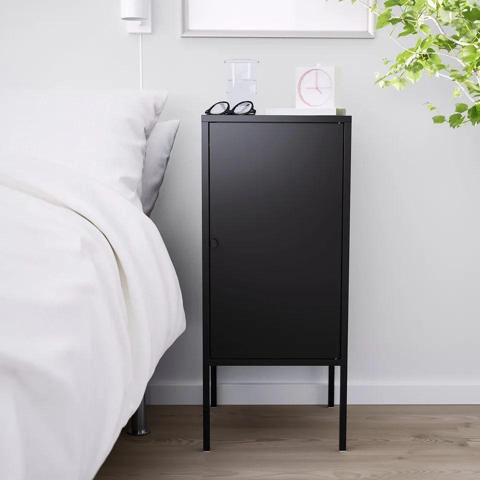 Black LIXHULT cabinet beside large white bed, small, metal.