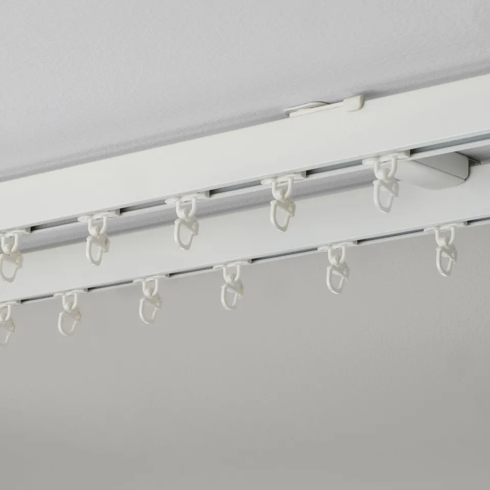 White ceiling-mounted curtain rod with several hooks, part of the VIDGA system for smooth gliding curtains.