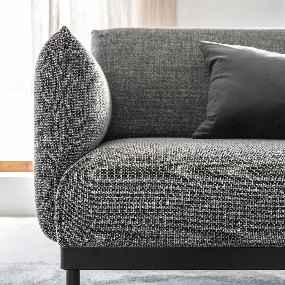 Modern grey sofa with cushions, sleek legs, and textured fabric.