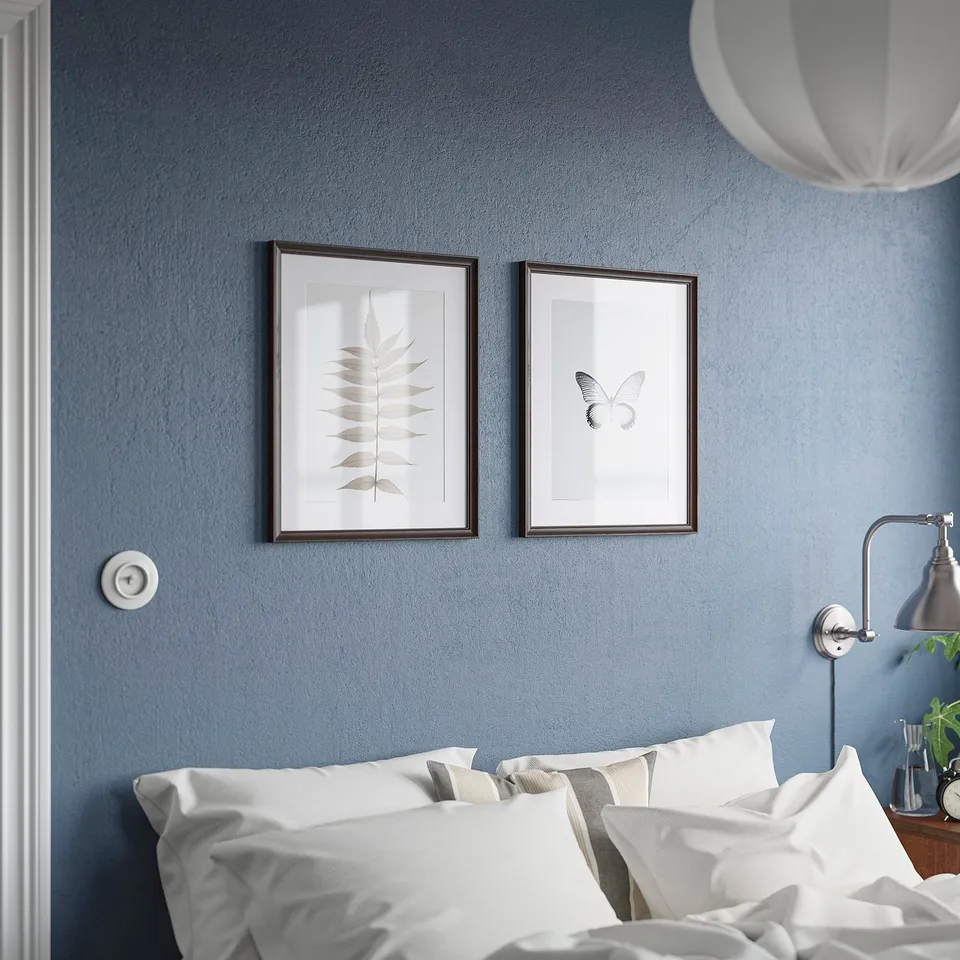 Two large framed art above bed with white & grey pillows, blue wall.