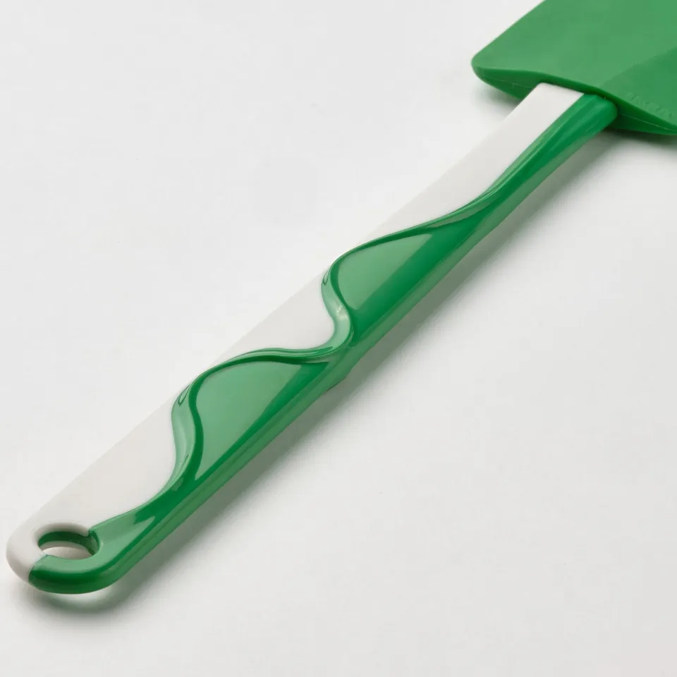 Green spatula with white pattern, flexible blade, ergonomic handle.