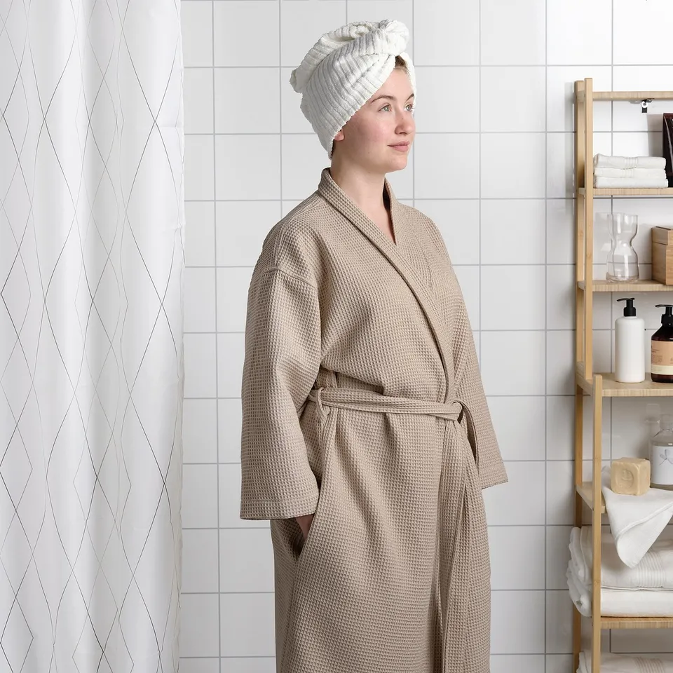 Young person modelling BJÄLVEN bathrobe with adjustable belt.