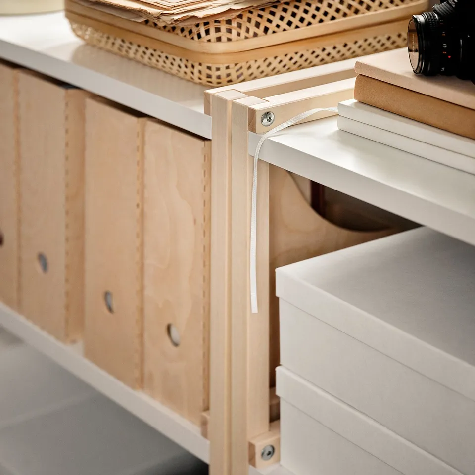An EKENABBEN wooden shelf unit with light wood finish, featuring open storage for easy access to items. Boxes and a camera are placed on the shelves.