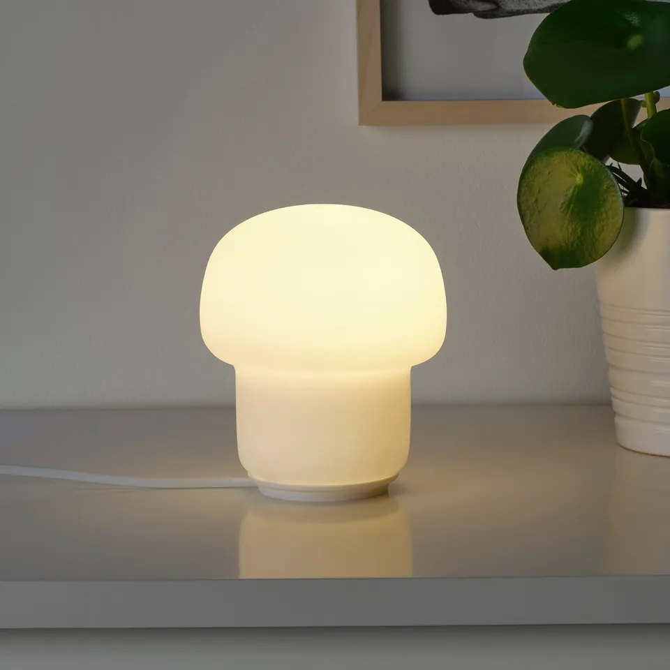 Small table lamp with soft glow, placed on a shelf. Blends modern style with mood lighting.
