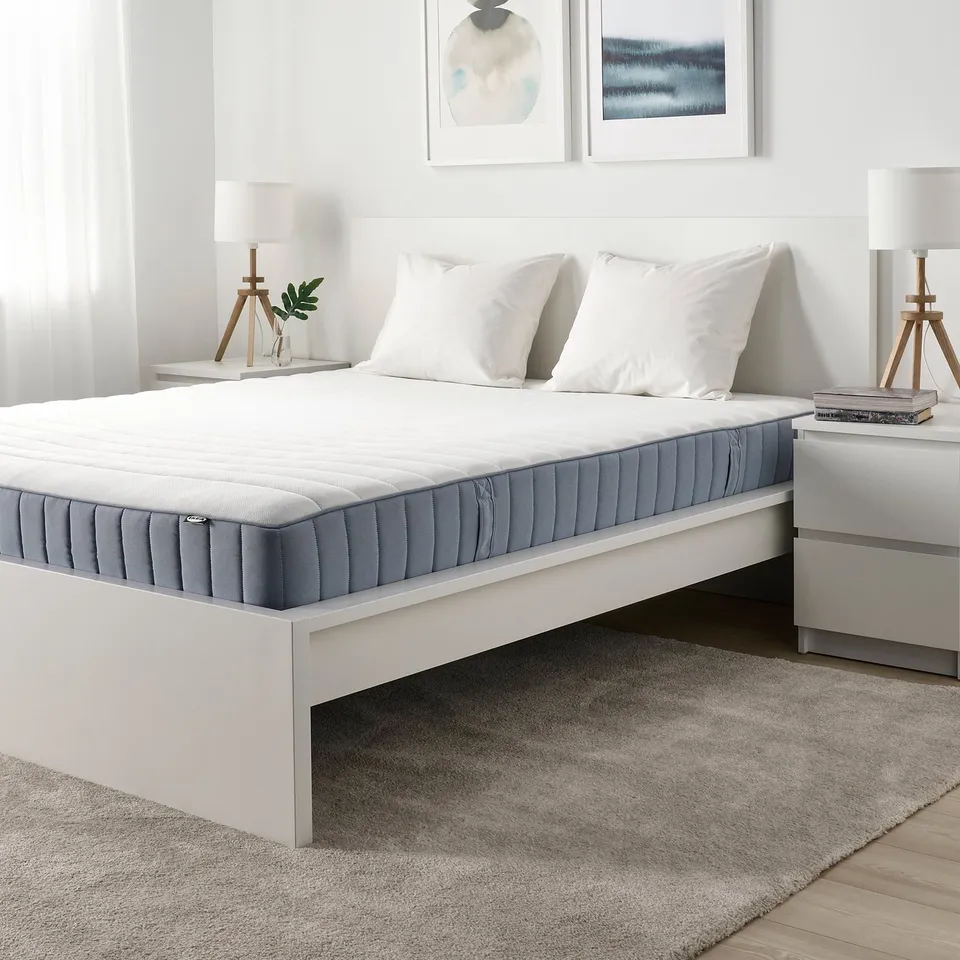 Minimalist bedroom with white IKEA VALEVÅG mattress on low platform bed, gray-blue, and neutral decor.