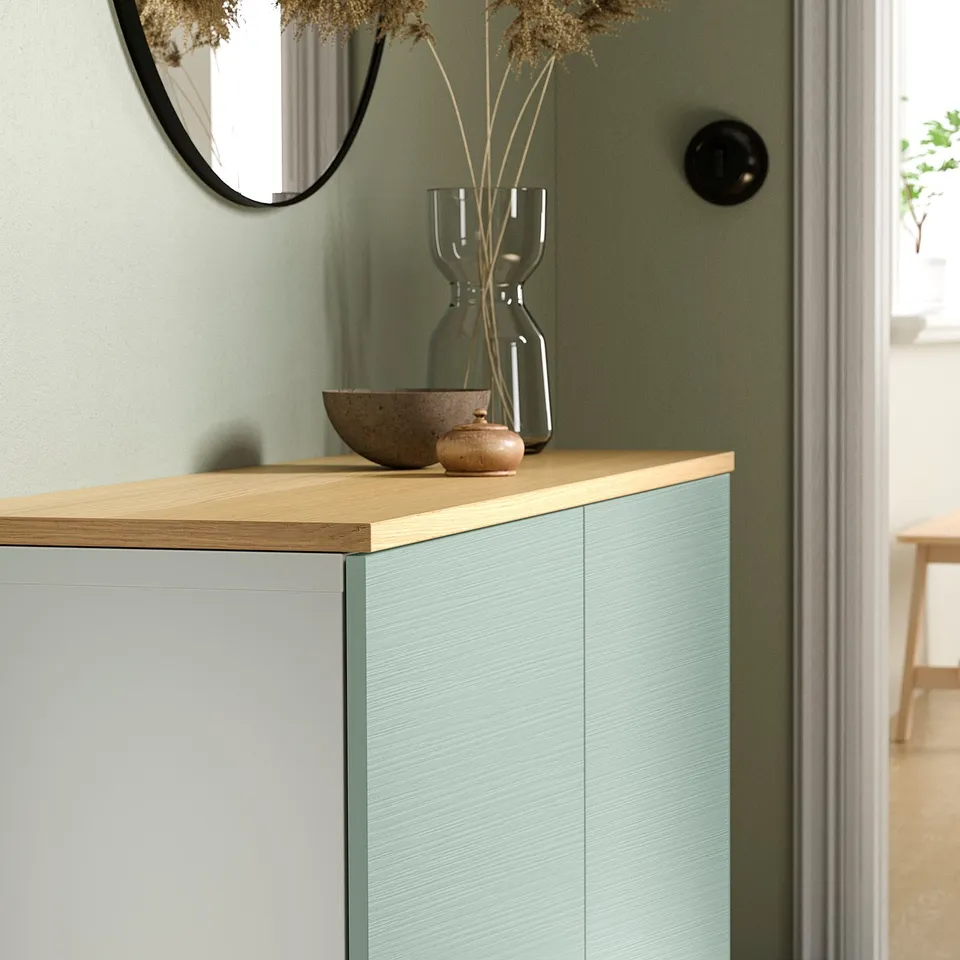 Modern sideboard with blue drawers, oak top, mirror, vase, and bowls. Fits well in light green room.