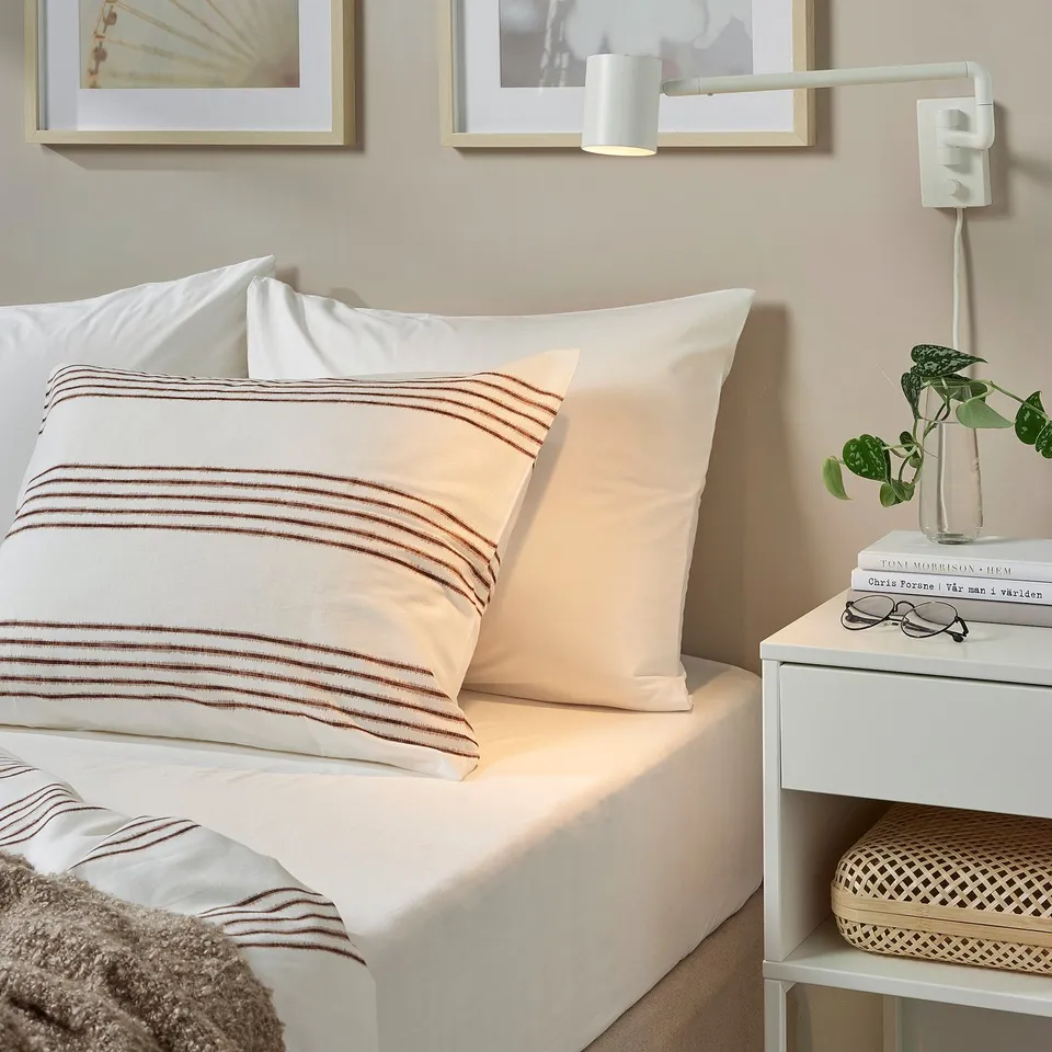 Bedroom with DVALA bedding, bedside table, and wall light.
