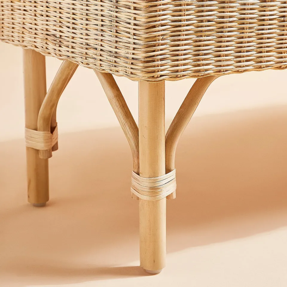 Wicker bench with intricate weave and sturdy bamboo legs, ideal for seating and storage.