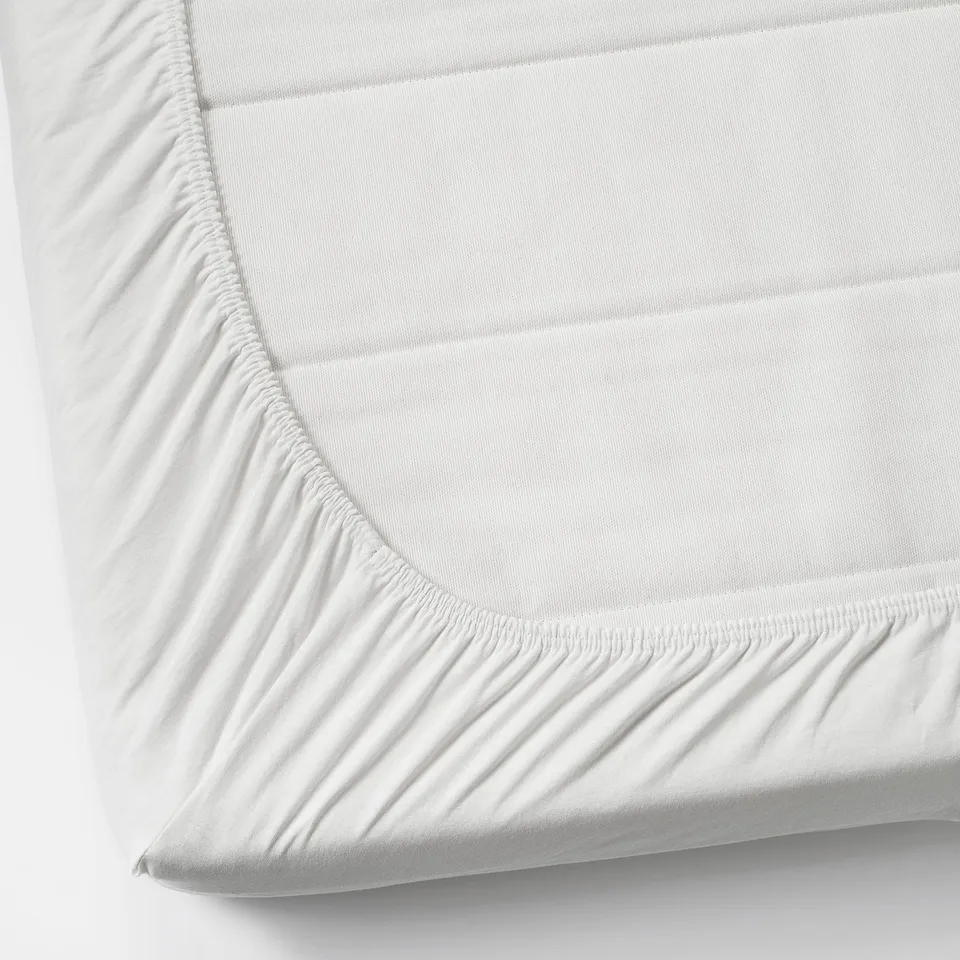 White fitted sheet with elastic corners, neatly stretched on a mattress.